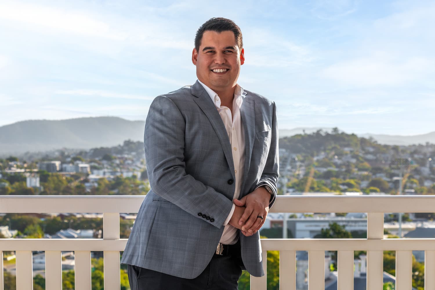 A brunette haired man in a white shirt and blue blazer, smiling for the camera